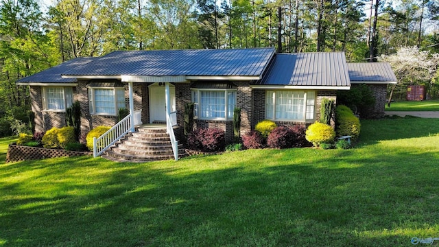 ranch-style home featuring metal roof, a front lawn, and brick siding