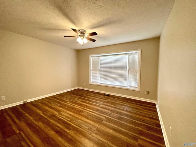 spare room featuring baseboards, ceiling fan, and dark wood-style floors