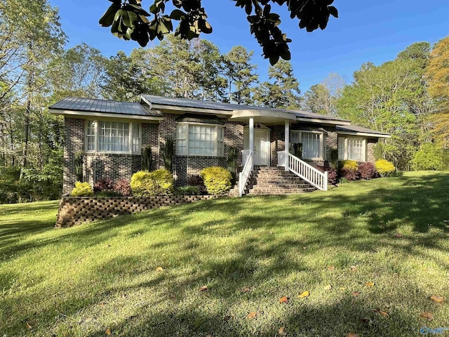 view of front of property with a front yard, brick siding, and metal roof