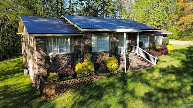 view of front of property with metal roof, a front lawn, and brick siding