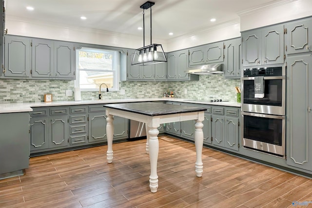 kitchen with sink, light hardwood / wood-style flooring, double oven, backsplash, and pendant lighting