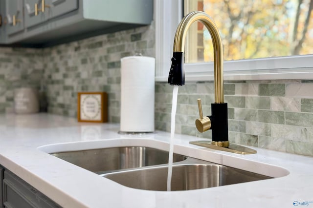 room details with backsplash, gray cabinets, and sink