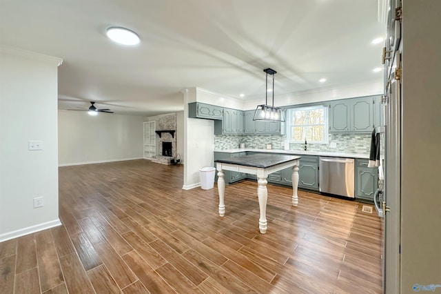 kitchen featuring ceiling fan, a stone fireplace, stainless steel dishwasher, crown molding, and hardwood / wood-style flooring