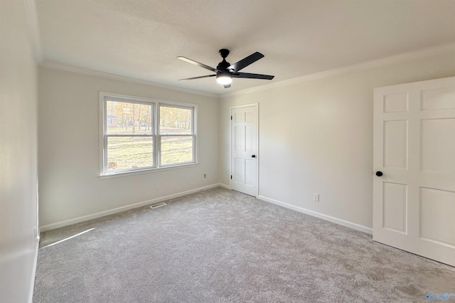 empty room with ceiling fan, ornamental molding, and light carpet