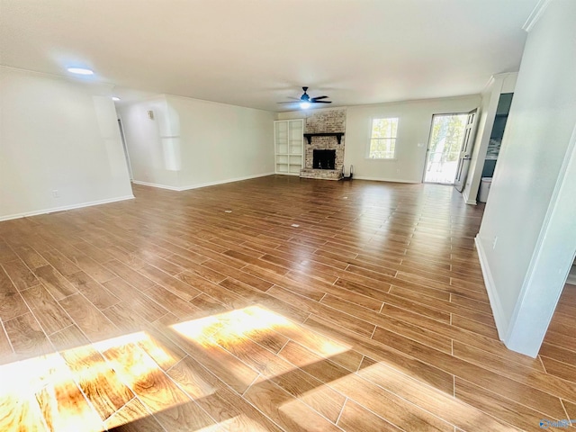 unfurnished living room featuring ceiling fan, wood-type flooring, and a brick fireplace