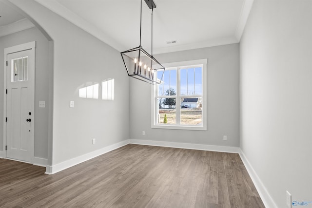 unfurnished dining area with hardwood / wood-style flooring, an inviting chandelier, and crown molding