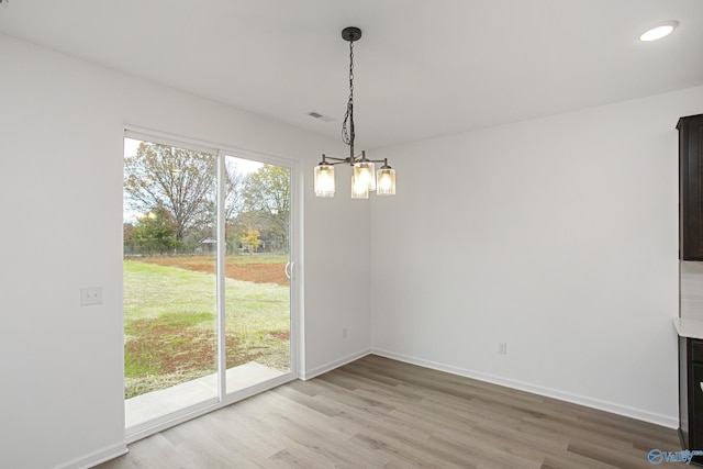 unfurnished dining area with a notable chandelier and wood-type flooring