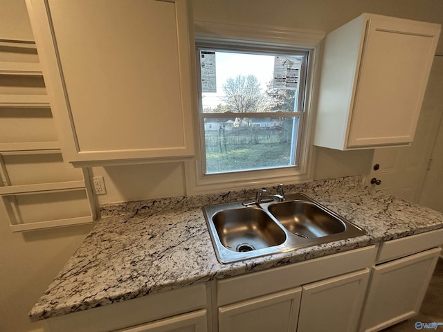 kitchen featuring white cabinetry, sink, and light stone countertops