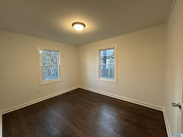 unfurnished room featuring a healthy amount of sunlight, ornamental molding, and dark wood-type flooring