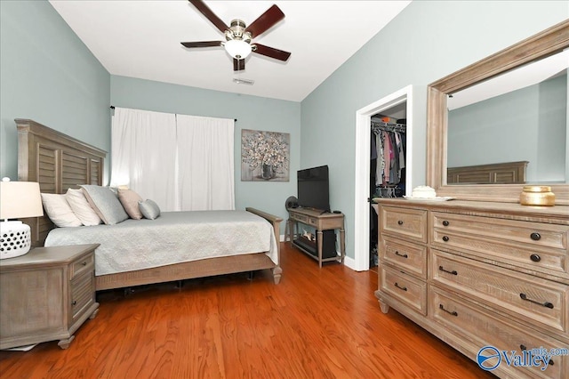 bedroom with a closet, a walk in closet, dark hardwood / wood-style flooring, and ceiling fan