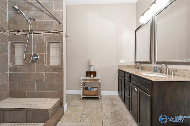 bathroom with tile patterned flooring, tiled shower, and vanity