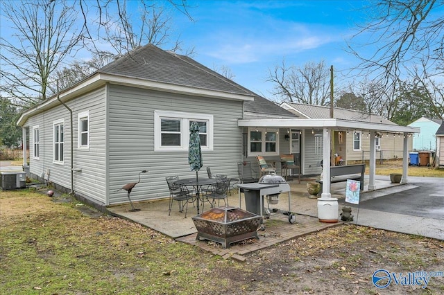 rear view of house with cooling unit, a fire pit, and a patio