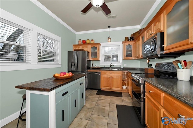kitchen with a kitchen island, stainless steel appliances, ornamental molding, light tile patterned flooring, and ceiling fan