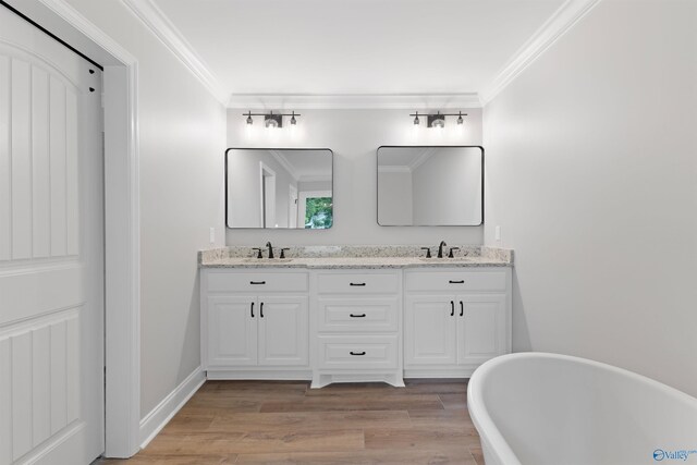 bathroom featuring ornamental molding, a freestanding bath, double vanity, and wood finished floors
