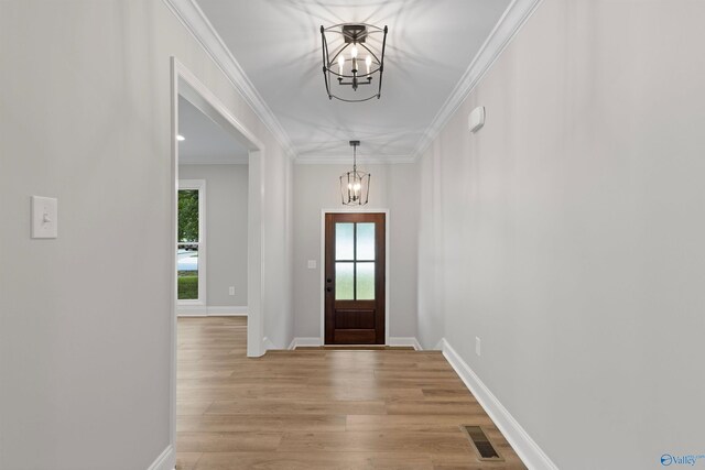 foyer with a chandelier, healthy amount of natural light, crown molding, and light wood-style flooring