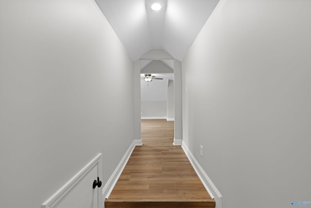 hall featuring wood finished floors, lofted ceiling, and baseboards