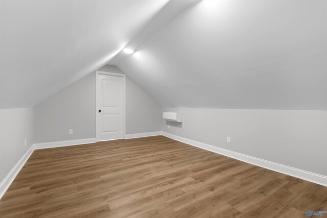 bonus room with vaulted ceiling, baseboards, and light wood-type flooring