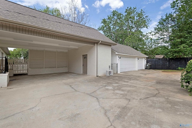 garage featuring fence, central AC unit, and a carport