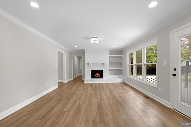 unfurnished living room with crown molding, light wood finished floors, baseboards, recessed lighting, and a brick fireplace