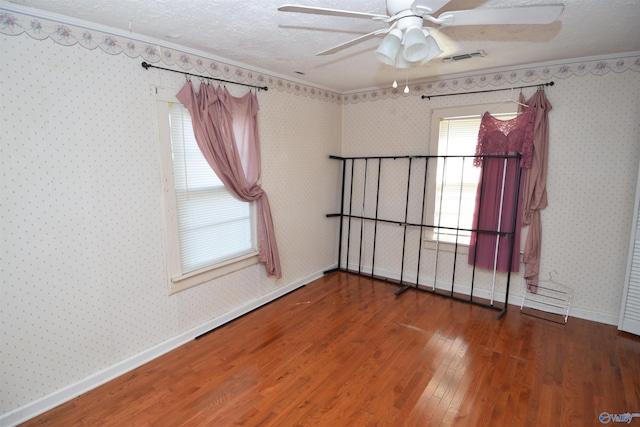 empty room featuring wood-type flooring, ceiling fan, crown molding, and a textured ceiling