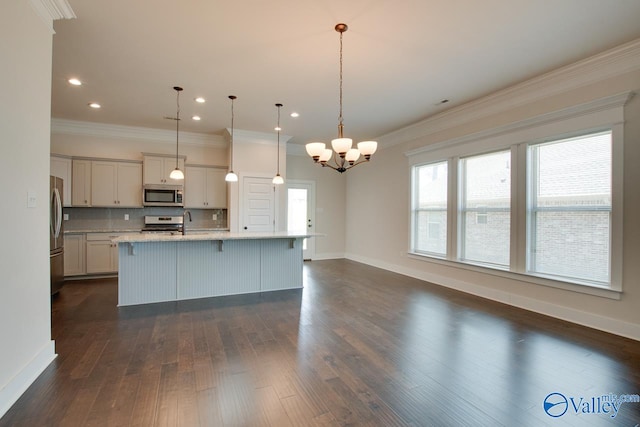 kitchen featuring stainless steel appliances, hanging light fixtures, an island with sink, ornamental molding, and dark hardwood / wood-style floors