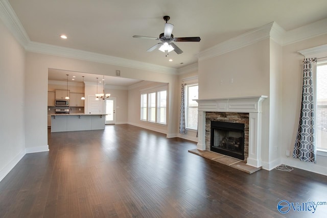 unfurnished living room featuring dark wood-type flooring, a wealth of natural light, a fireplace, and crown molding