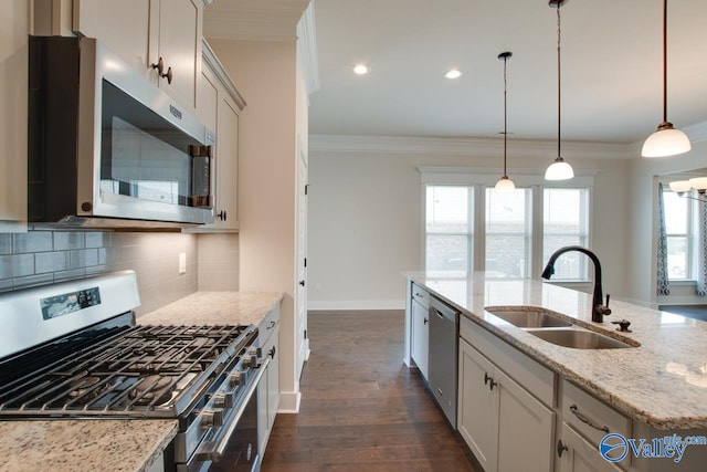 kitchen featuring stainless steel appliances, light stone counters, a healthy amount of sunlight, and sink