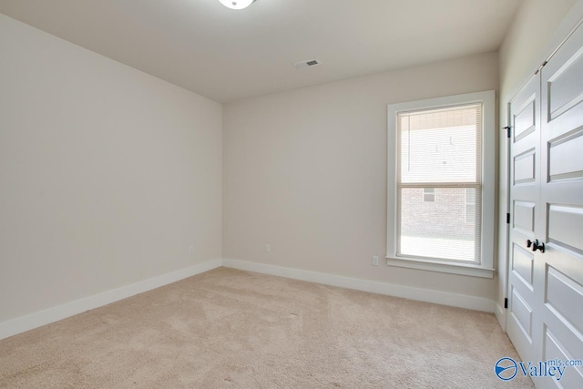 spare room with a wealth of natural light and light colored carpet