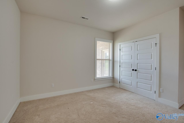 unfurnished bedroom featuring light carpet and a closet