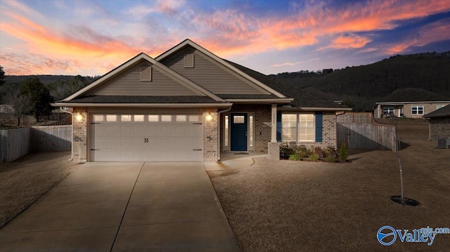 view of front of home featuring brick siding, fence, central air condition unit, concrete driveway, and an attached garage