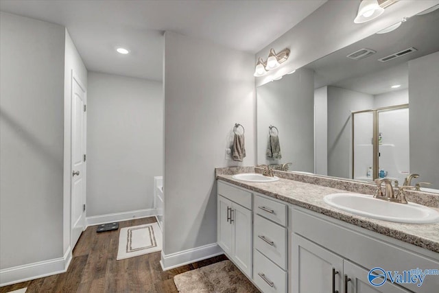 bathroom featuring a sink, visible vents, wood finished floors, and a shower stall