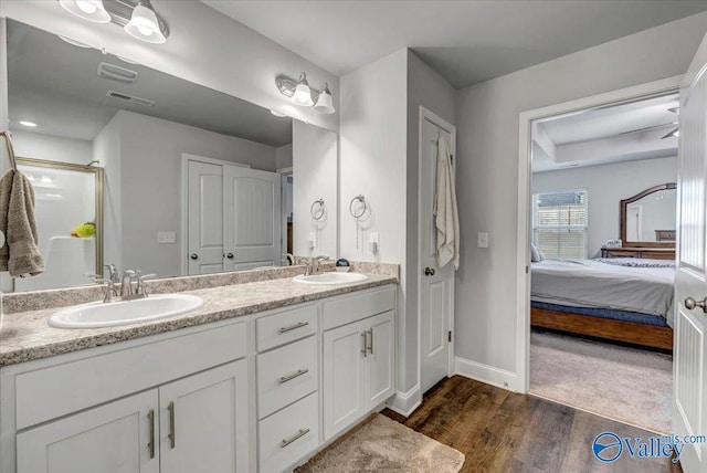 bathroom featuring wood finished floors, baseboards, ensuite bathroom, and a sink