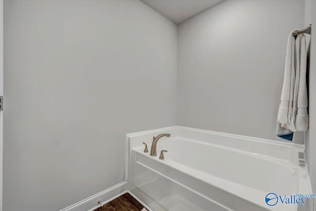 bathroom with a bath and baseboards