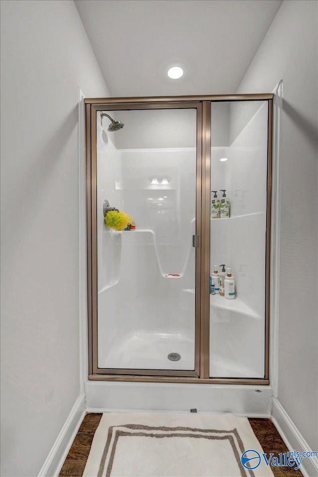 full bath featuring a shower stall, baseboards, and wood finished floors