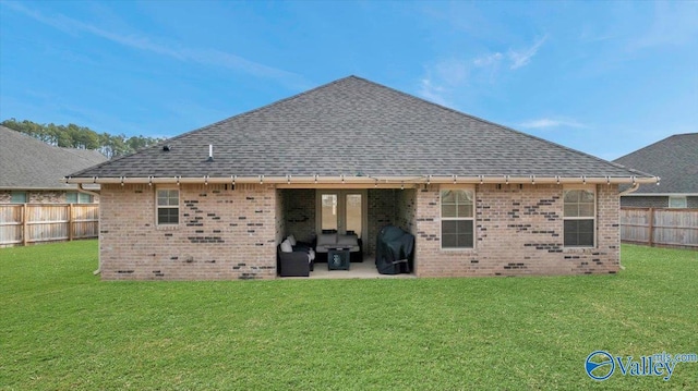 back of property with a patio, a fenced backyard, a yard, a shingled roof, and brick siding