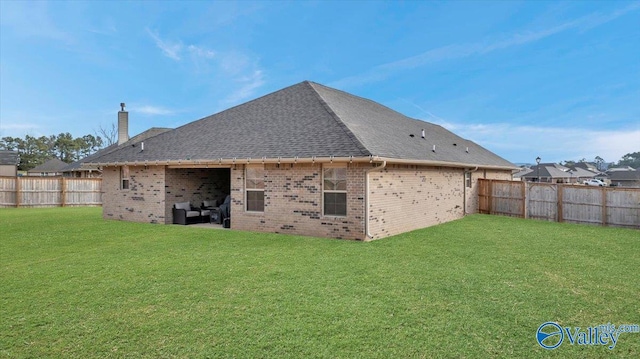 back of house with brick siding, a shingled roof, a lawn, a chimney, and a fenced backyard