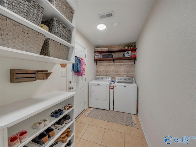 clothes washing area featuring visible vents, light tile patterned floors, baseboards, laundry area, and washing machine and dryer