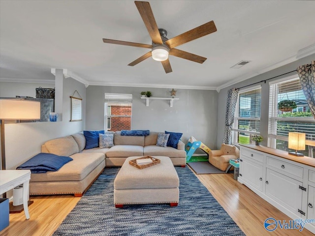 living area with visible vents, light wood-type flooring, ornamental molding, and ceiling fan