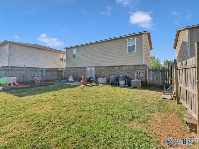 rear view of property featuring a yard, a fenced backyard, brick siding, and central air condition unit