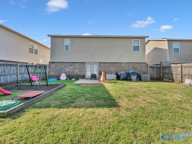 back of property with a yard, a fenced backyard, and brick siding