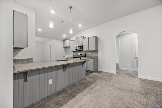 kitchen featuring decorative backsplash, a kitchen breakfast bar, gray cabinets, a sink, and stainless steel appliances