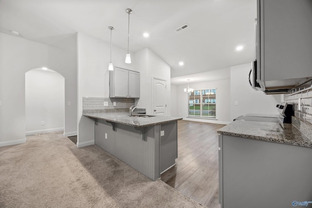 kitchen featuring appliances with stainless steel finishes, tasteful backsplash, arched walkways, a sink, and light stone counters