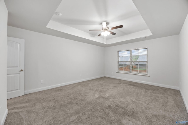 carpeted empty room featuring baseboards, a ceiling fan, and a tray ceiling