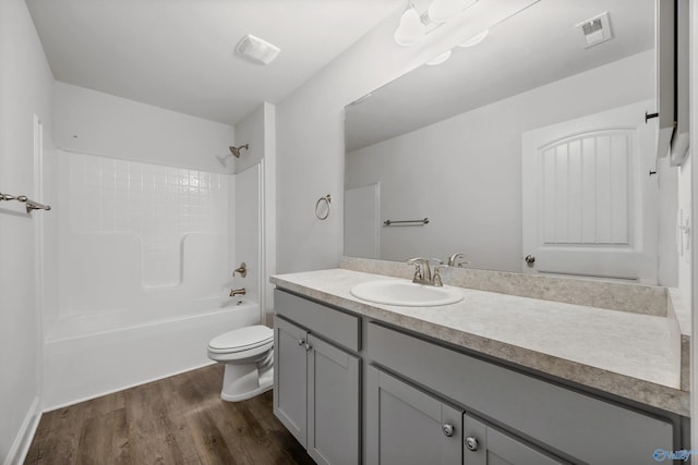bathroom with vanity, toilet, shower / washtub combination, wood finished floors, and visible vents