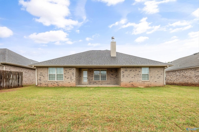 rear view of property featuring fence, a chimney, a yard, and brick siding