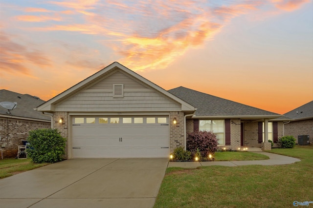 view of front of property with driveway, central AC unit, brick siding, a yard, and an attached garage