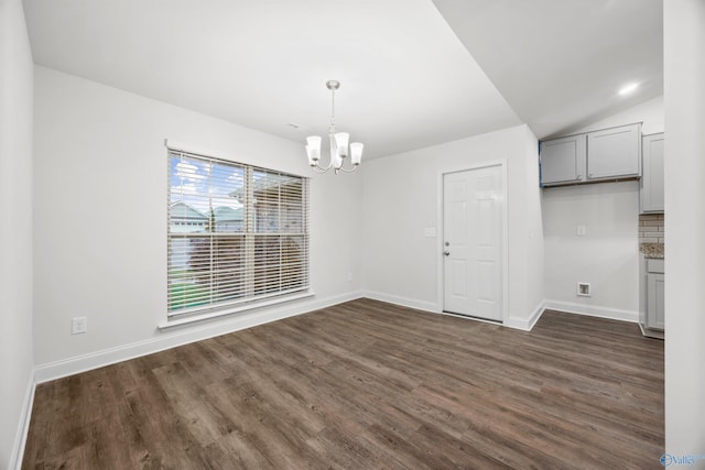 unfurnished dining area featuring an inviting chandelier, baseboards, dark wood-type flooring, and lofted ceiling