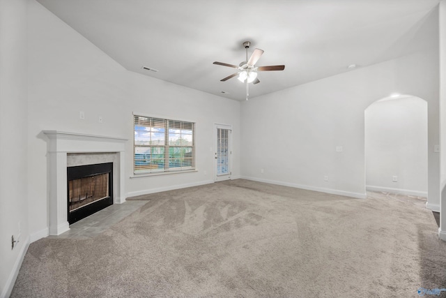 unfurnished living room featuring ceiling fan, a premium fireplace, arched walkways, carpet, and visible vents
