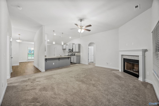 unfurnished living room with light colored carpet, arched walkways, a ceiling fan, lofted ceiling, and visible vents