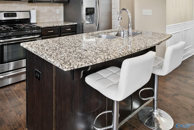 kitchen featuring sink, stainless steel appliances, an island with sink, and a breakfast bar